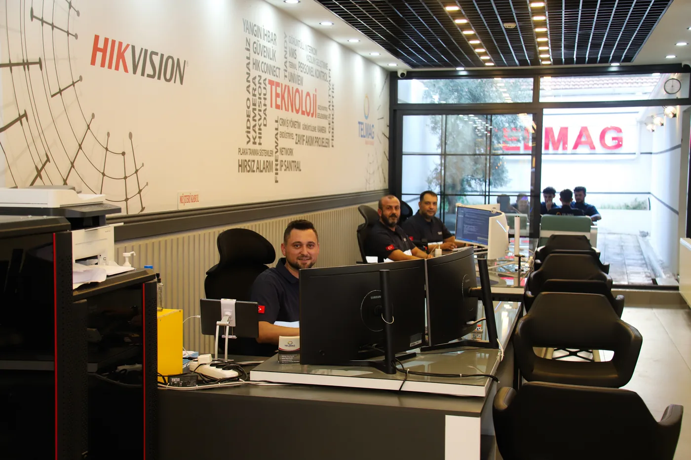 Telmag Bilişim ofisinde çift monitörlü çalışma masaları, iş istasyonları ve masa başındaki ekip