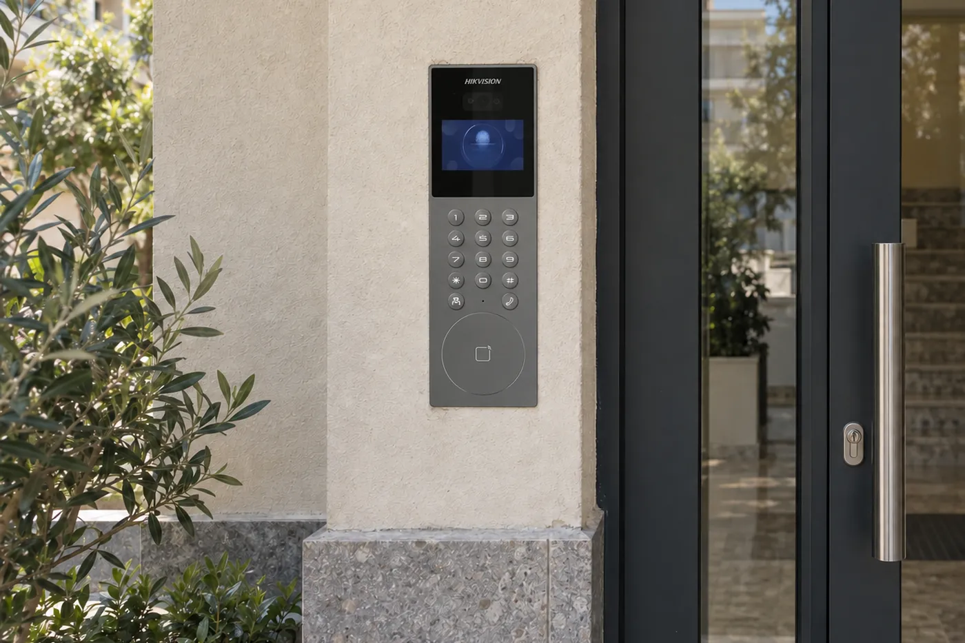 Çok daireli apartmanın cam giriş kapısı yanında sıva altına monte edilmiş Hikvision DS-KD9203-E6 kapı paneli