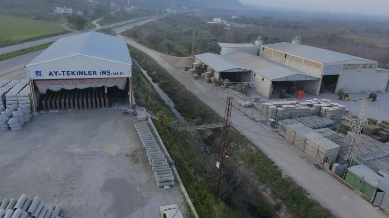 Aytekinler İnşaat üretim tesisinde firma tabelalı depo hangarı ve beton boru stok sahası (firma görseli)